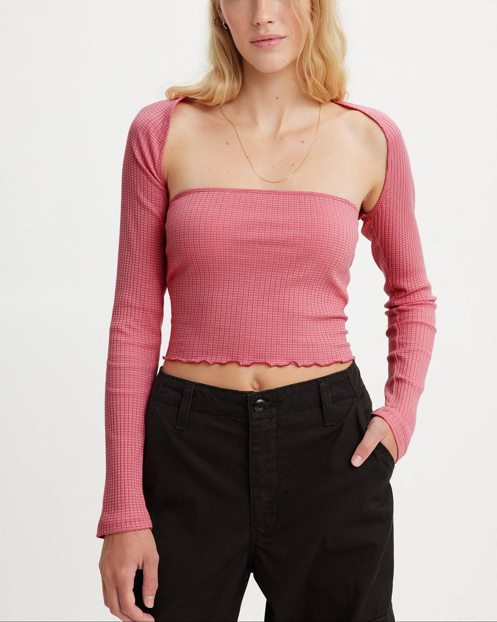 Woman wearing a pink ribbed long-sleeve top with a scalloped hemline on a white background.