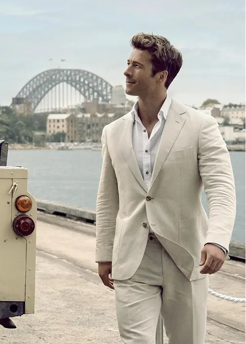 Man and woman standing next to a vintage vehicle with a scenic background