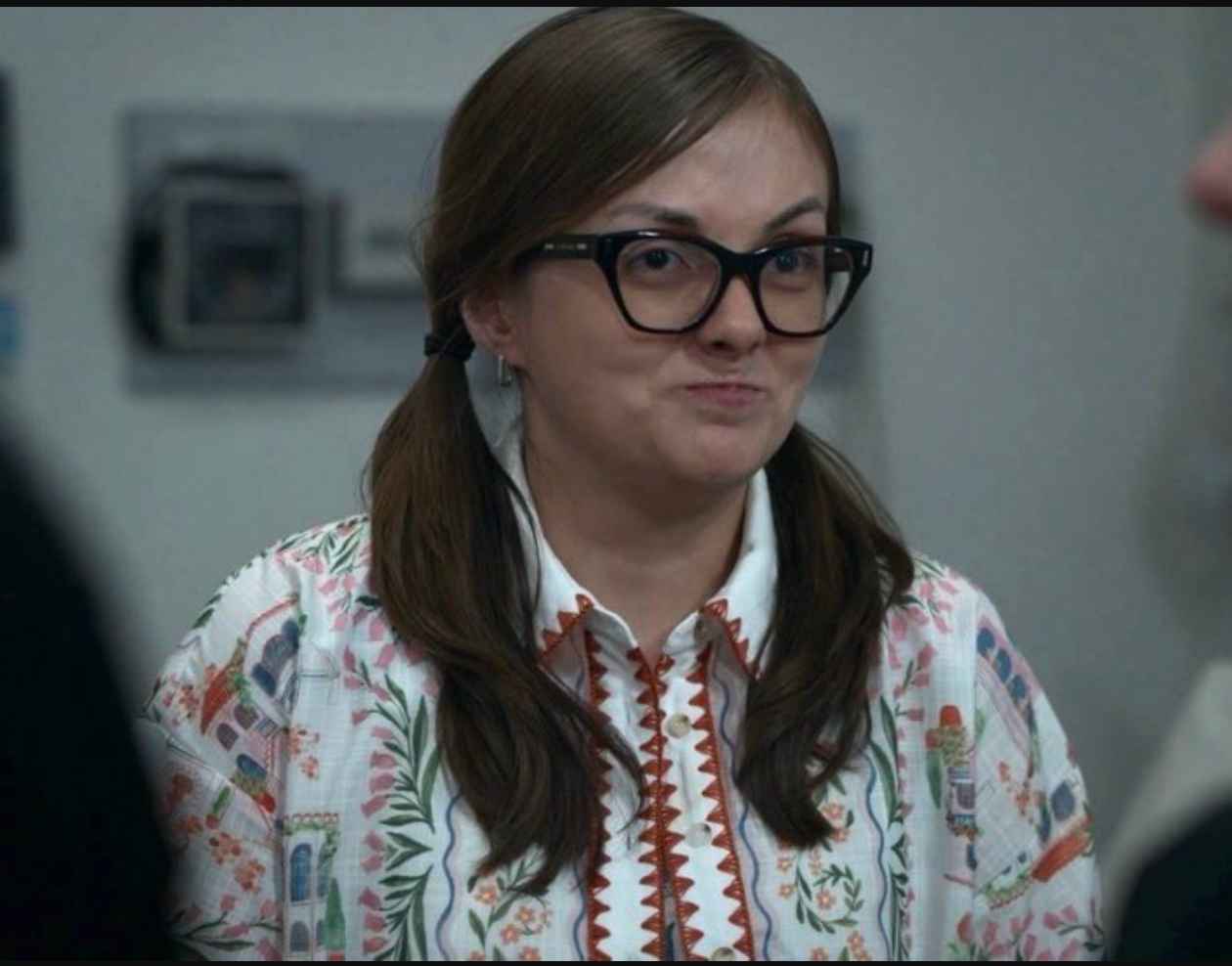 Woman wearing glasses and a patterned shirt in an indoor setting