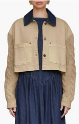 Person wearing a beige knitted jacket over a navy outfit on a white background