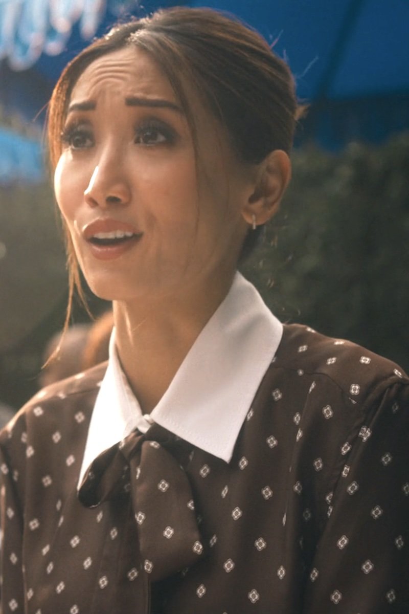 Woman wearing a brown patterned blouse with a white collar outdoors