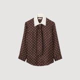 Brown polka dot blouse with white collar on a light gray background