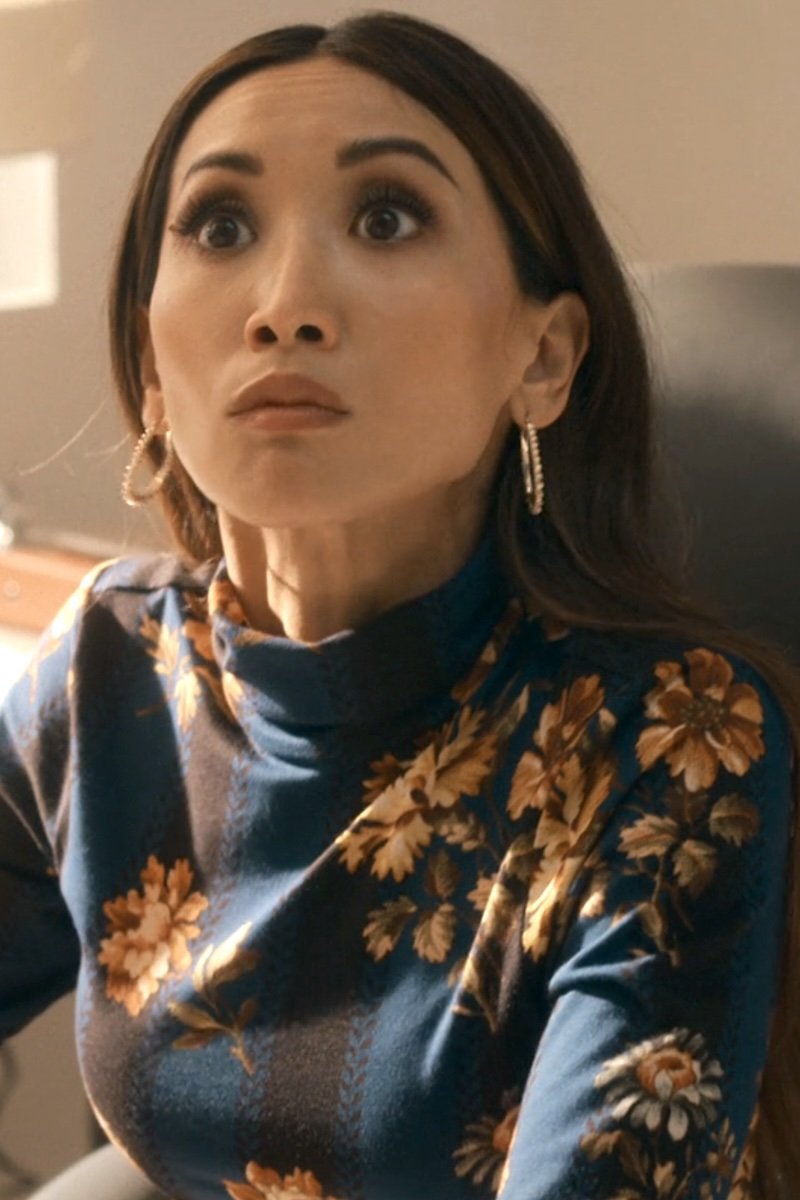 Woman wearing a blue floral sweater with a neutral background