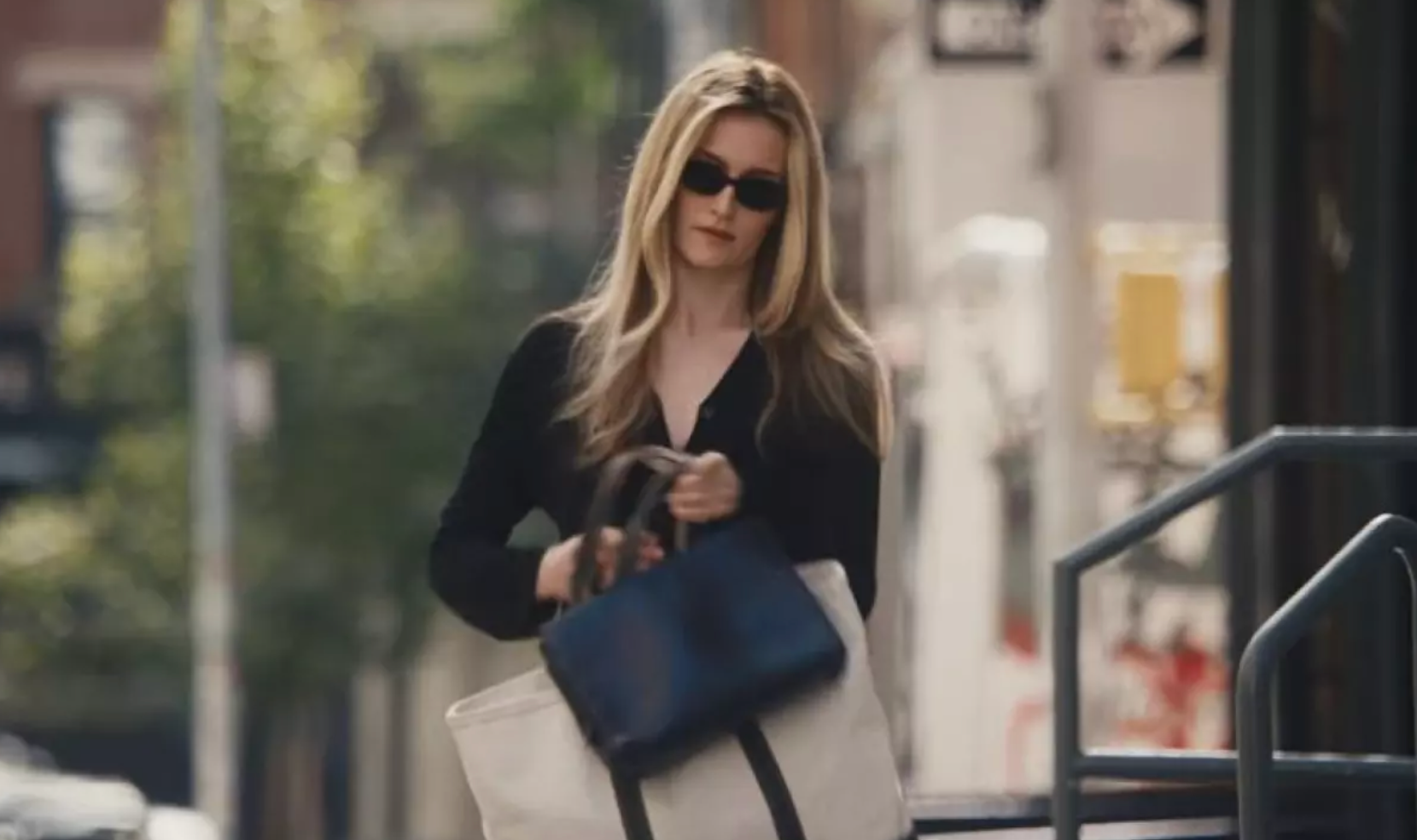 Woman walking outdoors holding a blue and white bag
