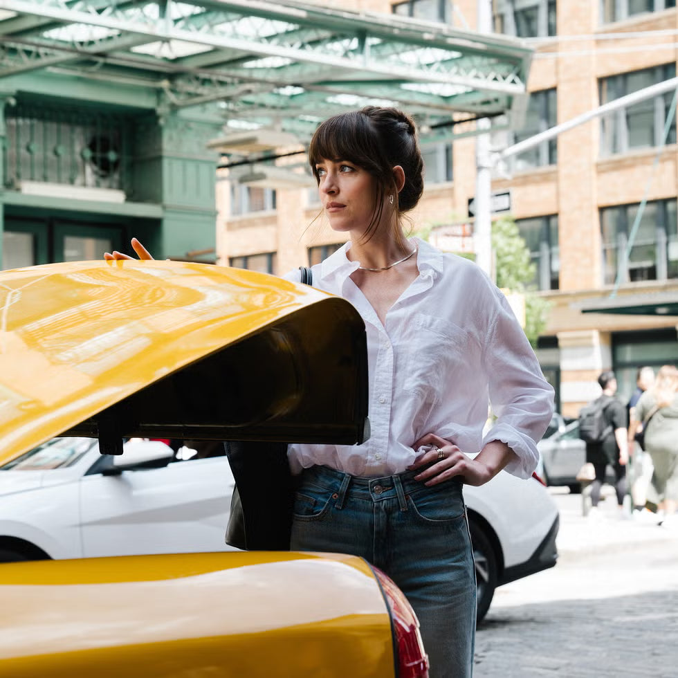 Woman standing next to a yellow car with a cityscape background