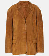 A tan suede blazer jacket with notch lapels, three front buttons, and flap pockets, shown against a plain light gray background. The brand name 'STAUD' is faintly visible on the inner neck label.