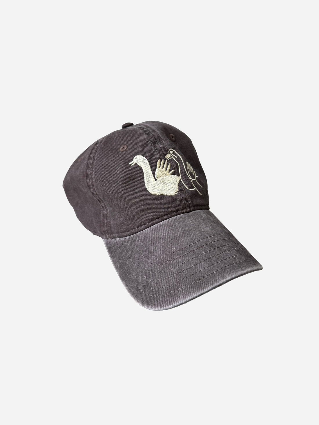 A dark gray washed baseball cap featuring an embroidered design of a white goose and a black silhouette of a person holding a lantern, set against a plain light gray background.