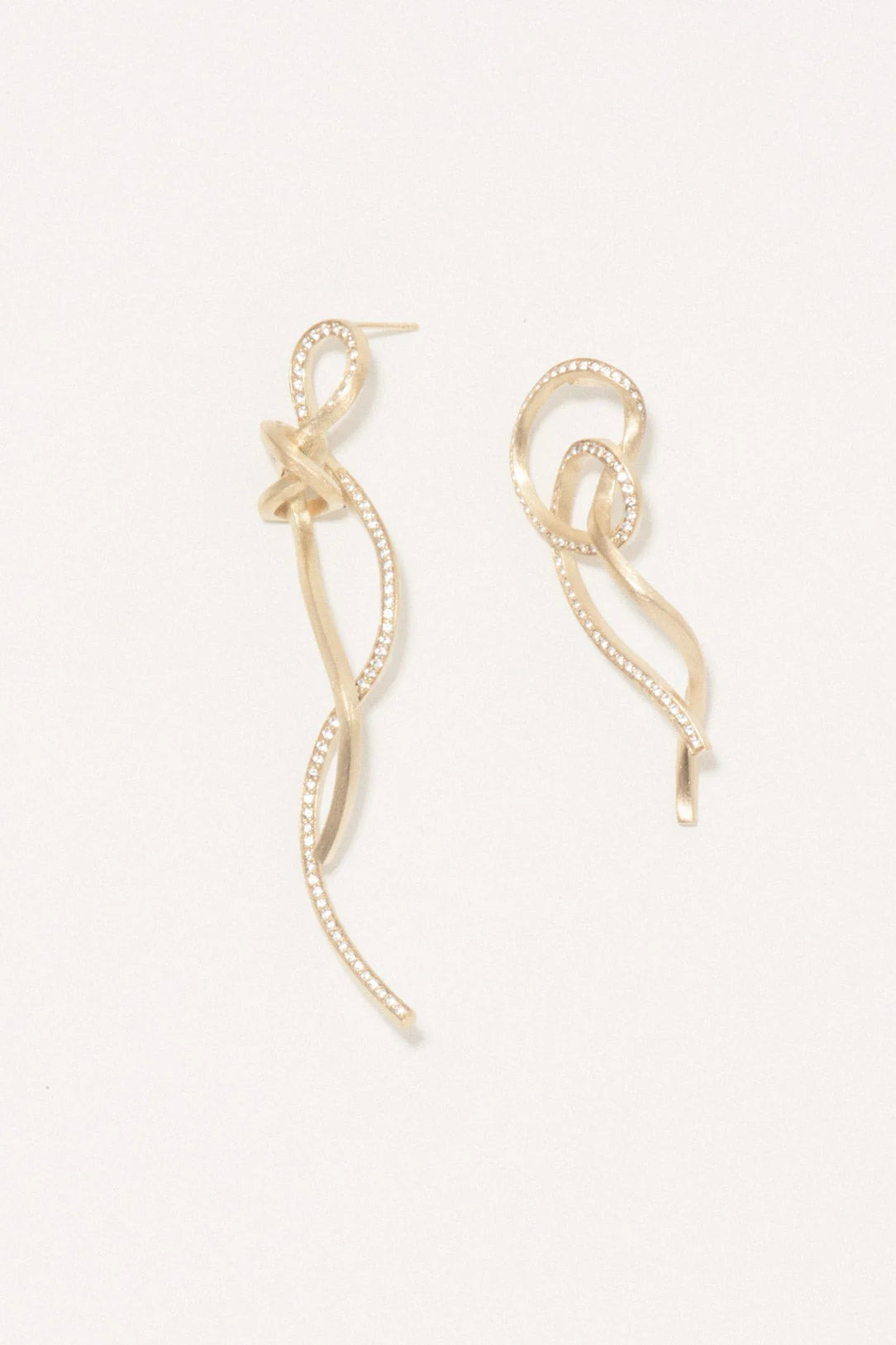 Gold earrings on a light beige background