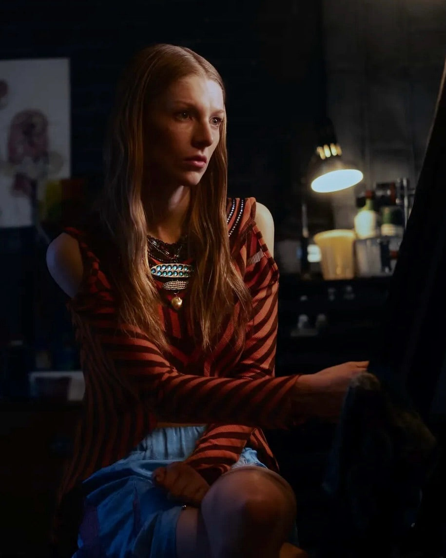 Woman sitting in a dimly lit room with a lamp in the background