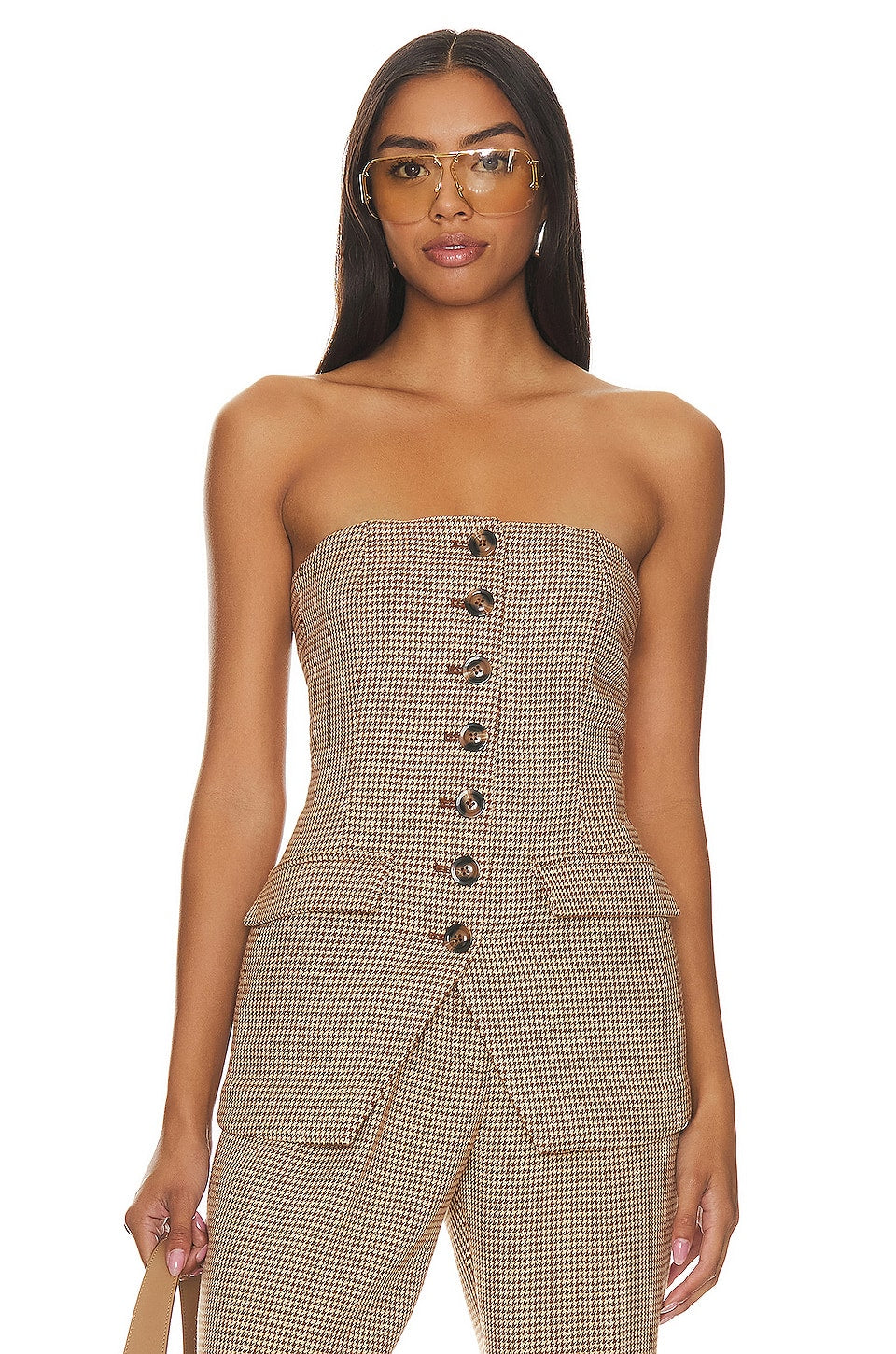 Woman wearing a strapless houndstooth patterned top and pants on a white background