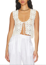 Woman wearing a white crochet top and white pants on a white background
