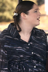Woman wearing a black and white patterned shirt with braided hair.