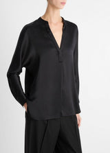 Person wearing a black blouse with a V-neck and long sleeves on a white background