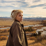 Woman standing in a scenic landscape with mountains and rivers.
