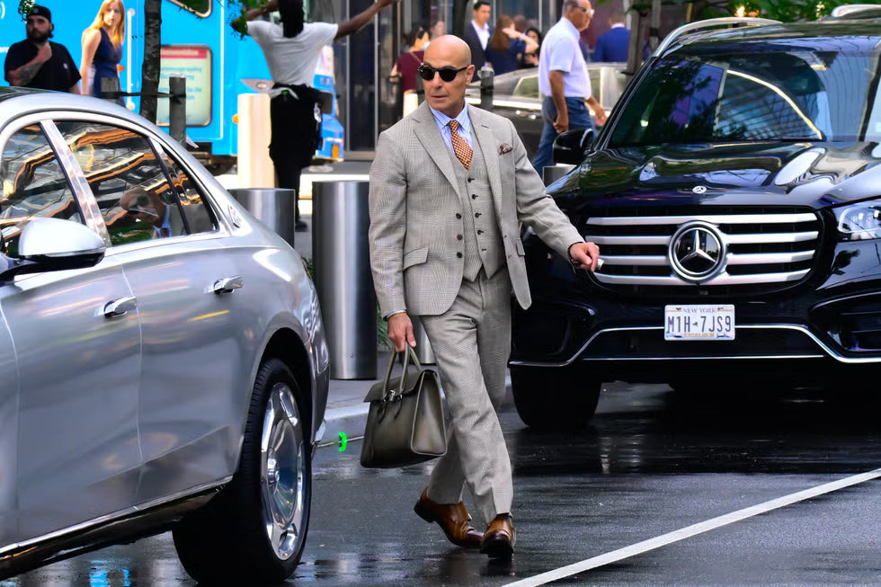 Man in a suit walking between two cars on a city street