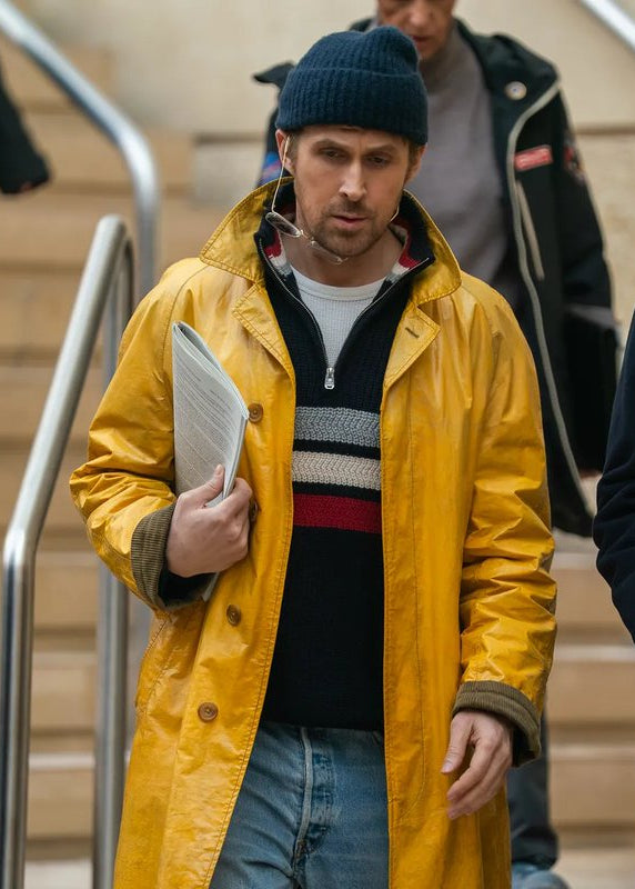 Two men walking outdoors, one in a yellow raincoat and the other in a suit with a tie.