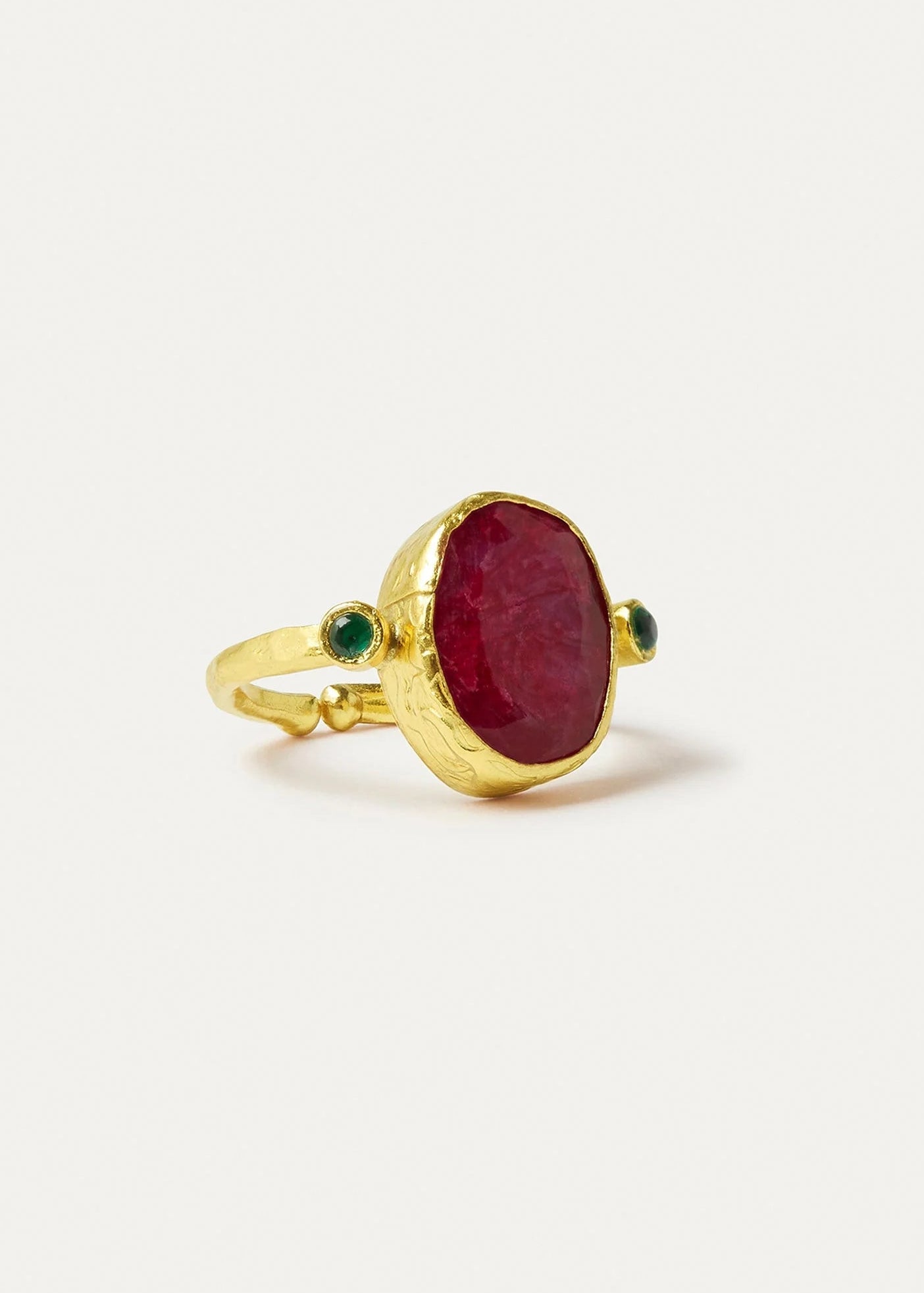 Gold ring with a red stone and green accents on a white background