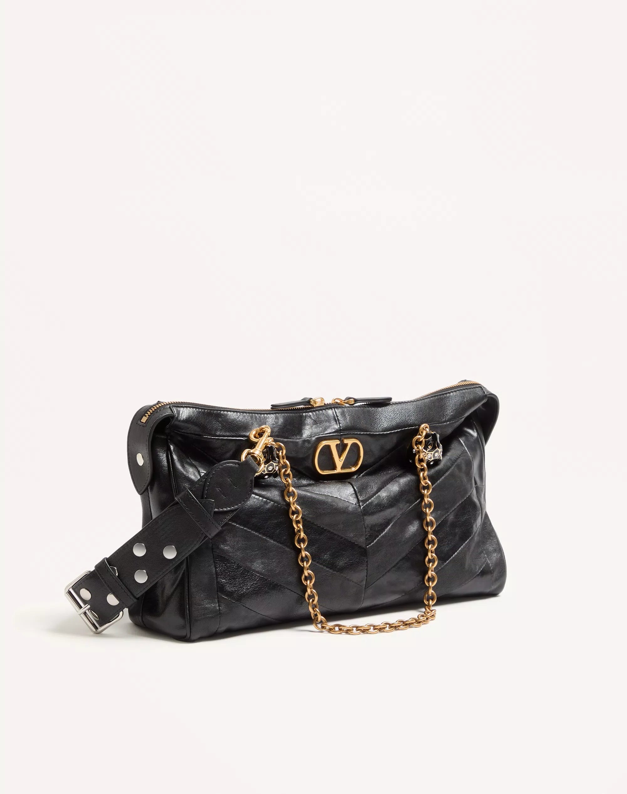 Black handbag with gold chain and logo on a light beige background