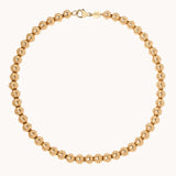 Gold beaded necklace on a white background