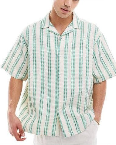 A man wearing a short-sleeve button-up shirt with vertical green and white stripes, styled with white trousers and sunglasses on his head, against a plain white background. The ASOS logo is visible in the top right corner.