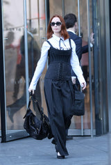 Woman in a black pinstripe dress with a white shirt walking outdoors.
