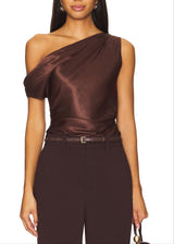 Woman wearing a brown one-shoulder top and pants on a white background