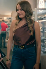 Woman wearing a brown one-shoulder top and blue jeans in an indoor setting