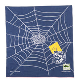 Blue fabric with white spider web design, yellow spider, and white square with floral pattern on a white background.