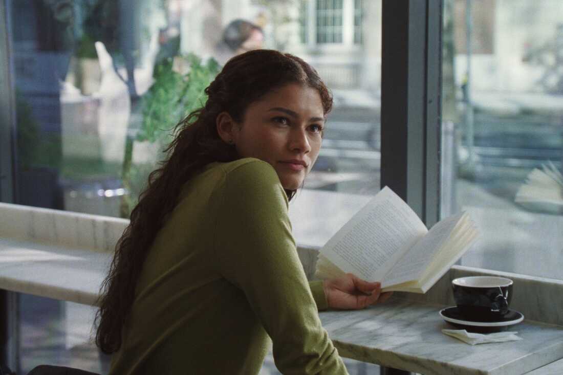 Woman reading a book at a cafe with a cup of coffee on the table.