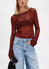 Woman wearing a red knit top and blue denim shorts on a white background